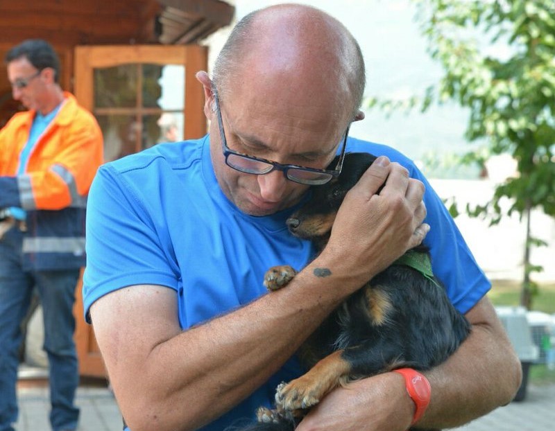 Uomo abbraccia cagnolino ritrovato dopo terremoto